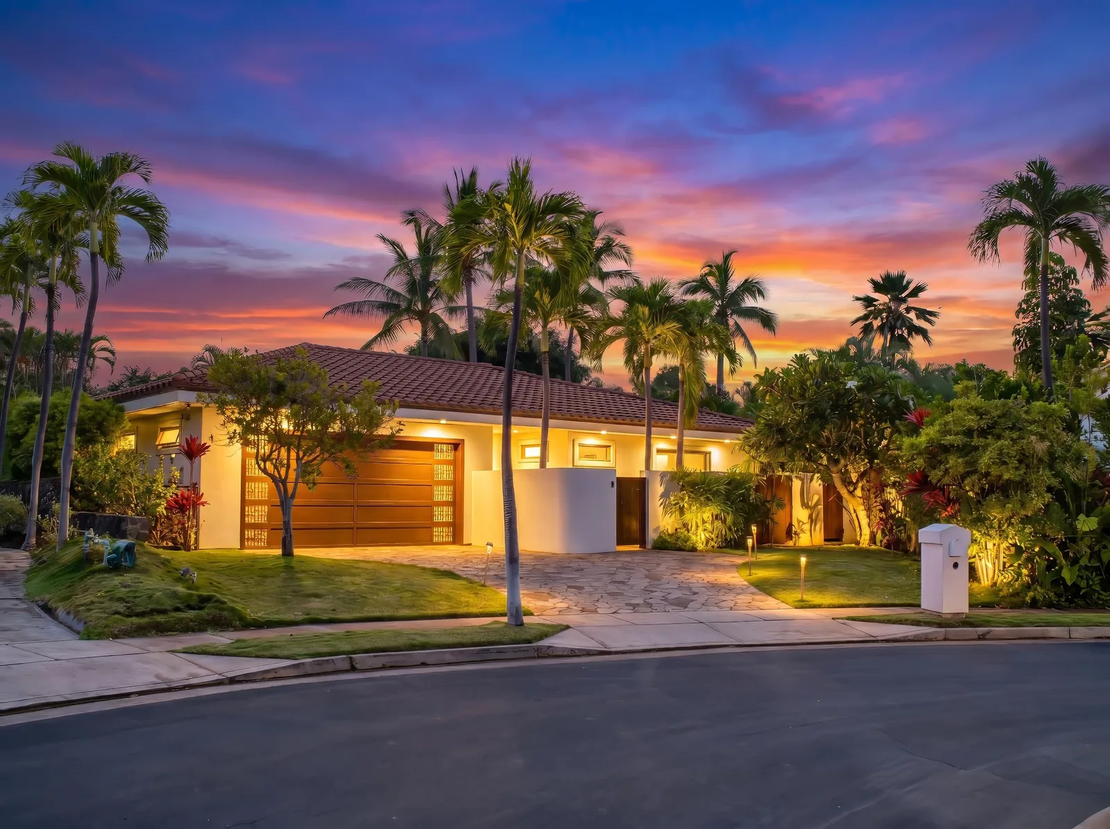 A Wailea estate glowing at twilight, framed by palms against a pink and gold Maui sunset sky